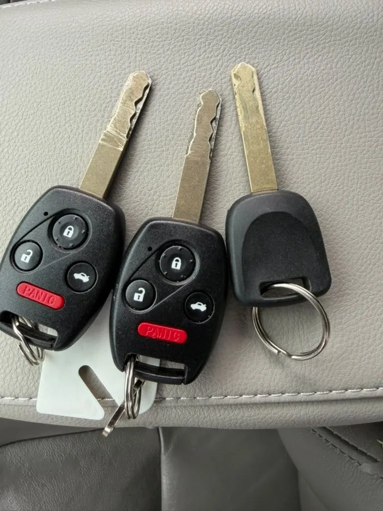 Three vehicle keys, two with remote buttons, resting on a car seat.