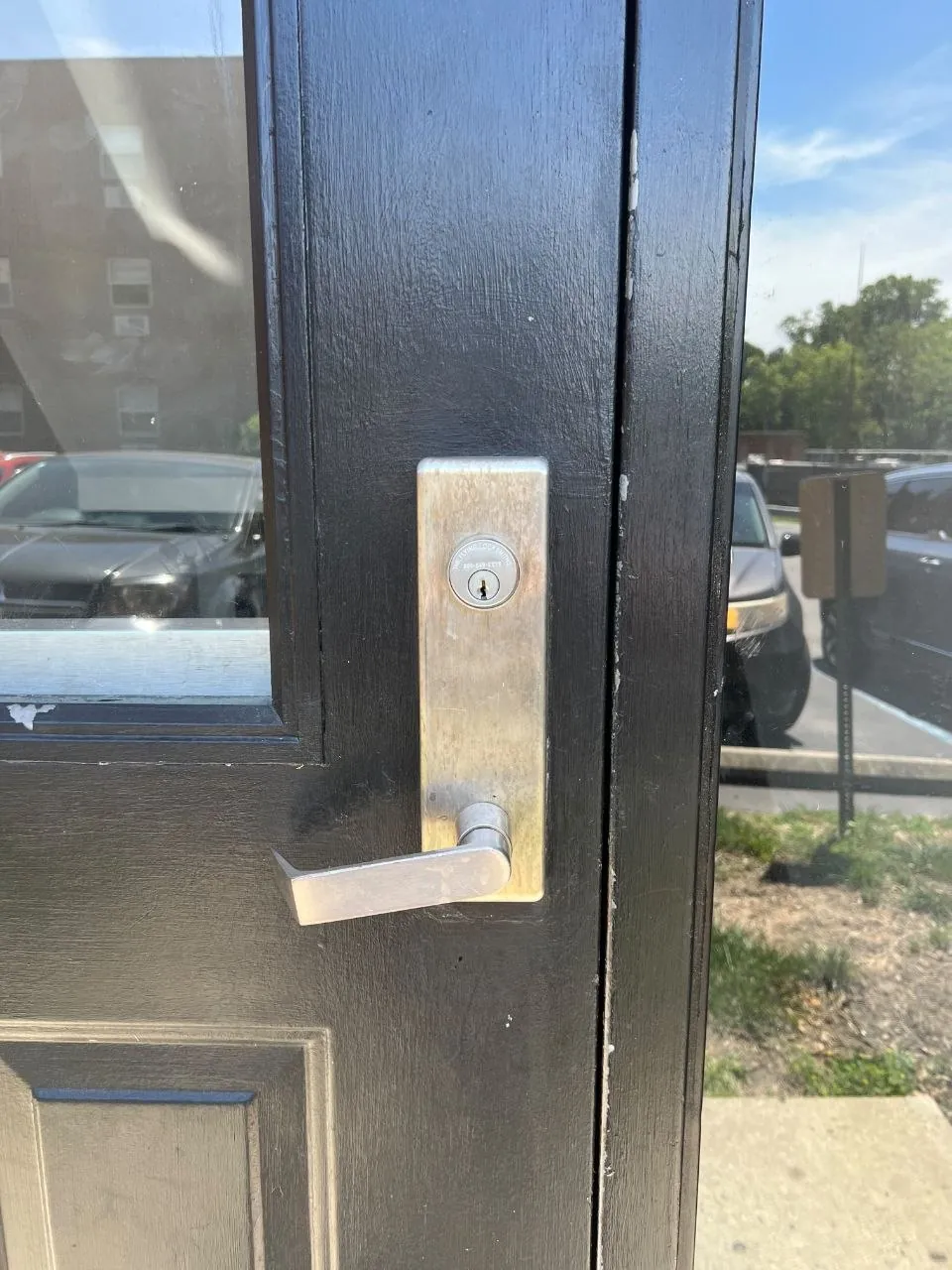 Lever handle with a key cylinder on a commercial entrance door.
