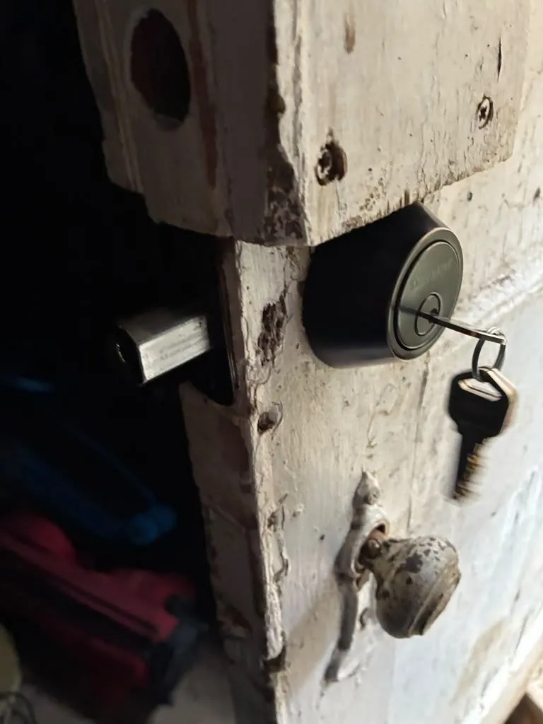 New deadbolt with the key in it, fitted on an old weathered door.