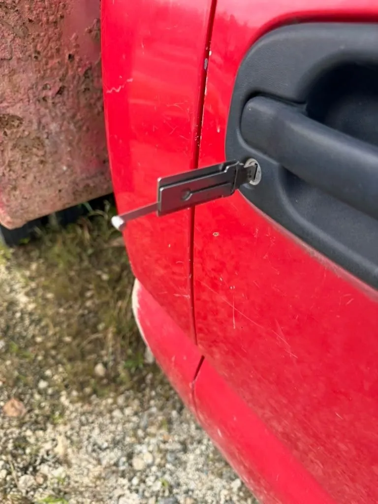 Key in the door lock of a red car.