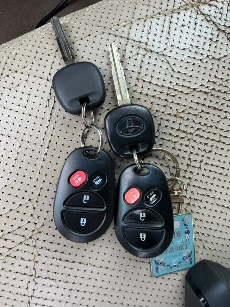 Vehicle keys and remotes on a key ring, laid on a car seat.