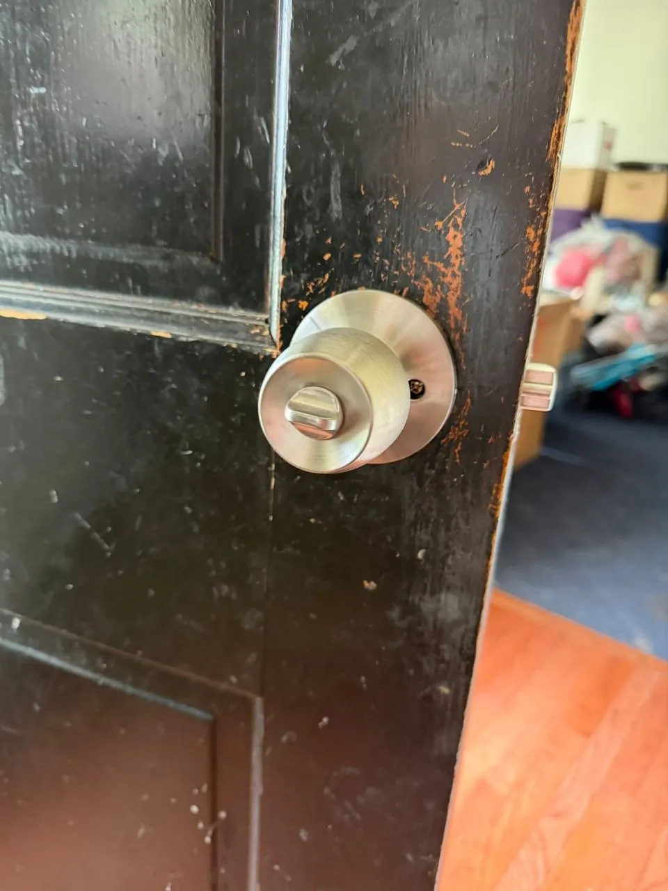 Brushed steel knob lock on a black painted door.
