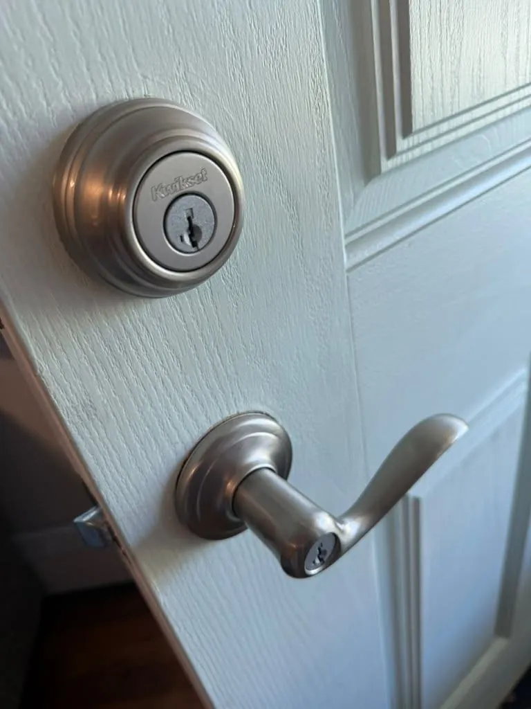 New deadbolt and lever handle fitted on a white front door.