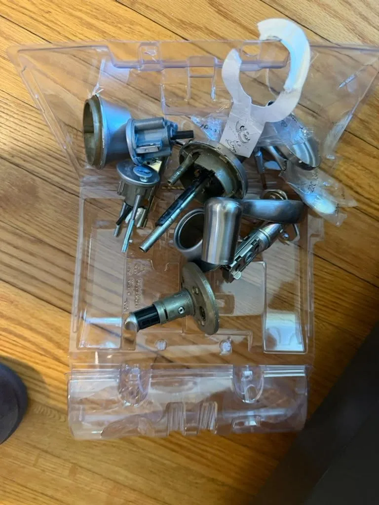Old lock cylinders and parts collected in a clear plastic tray after a lock change.