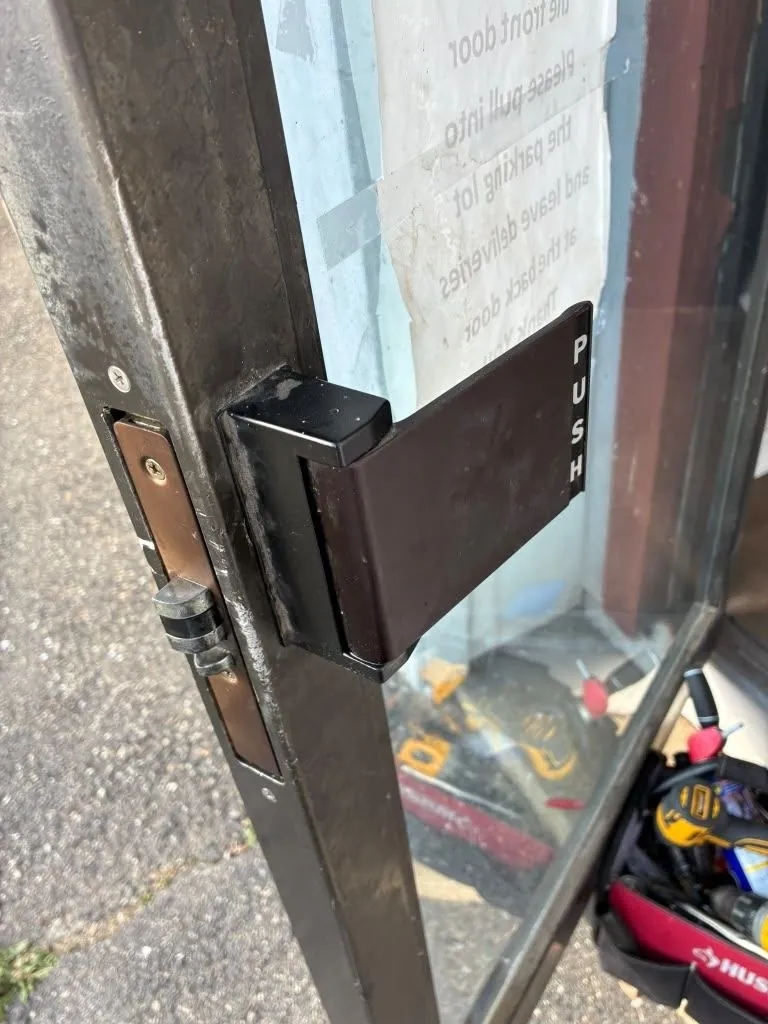 Storefront door with a latch guard marked push over the edge of the lock.